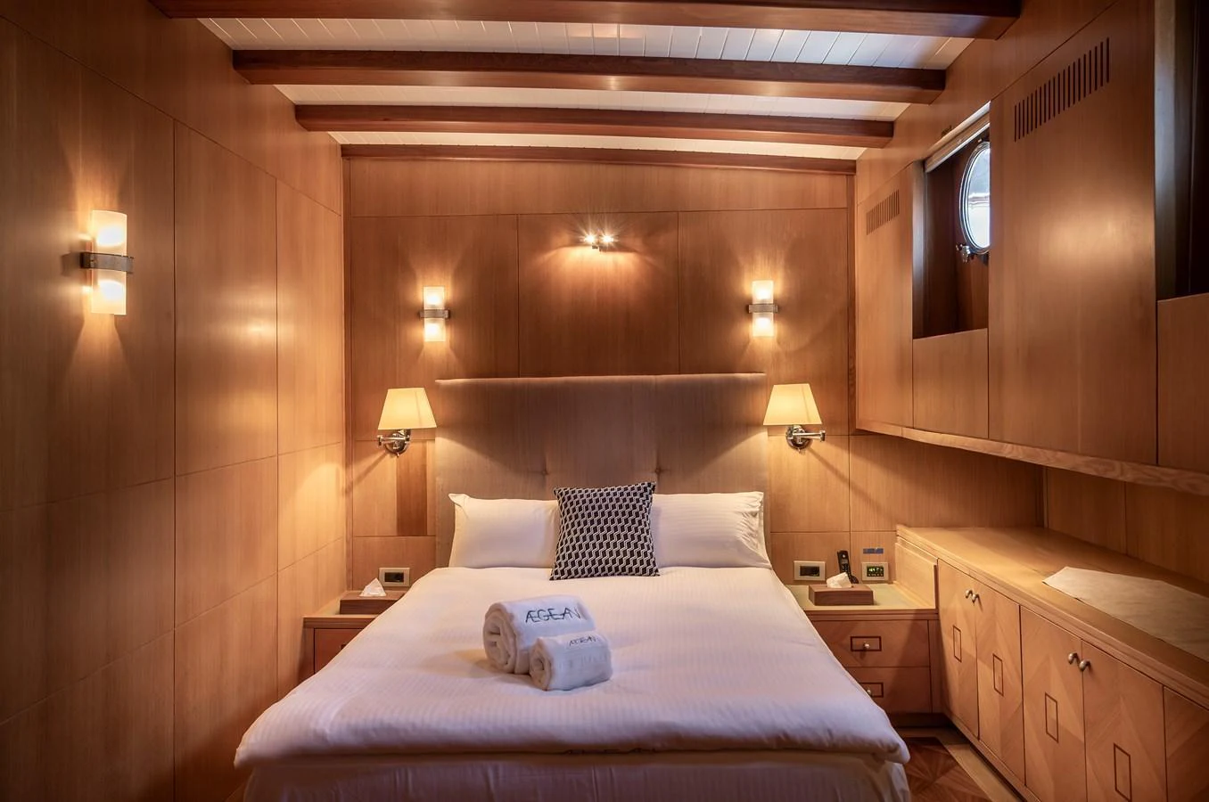 The stateroom features warm wood paneling and cozy lighting, creating an inviting and comfortable atmosphere. aboard AEGEAN Yacht for Sale