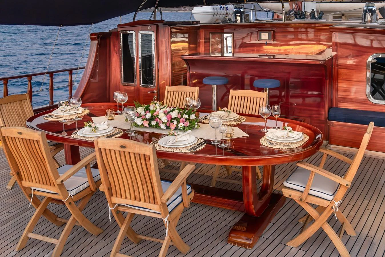 The aft deck features an elegant dining area with a polished wooden table and comfortable chairs, perfect for alfresco dining. aboard AEGEAN Yacht for Sale