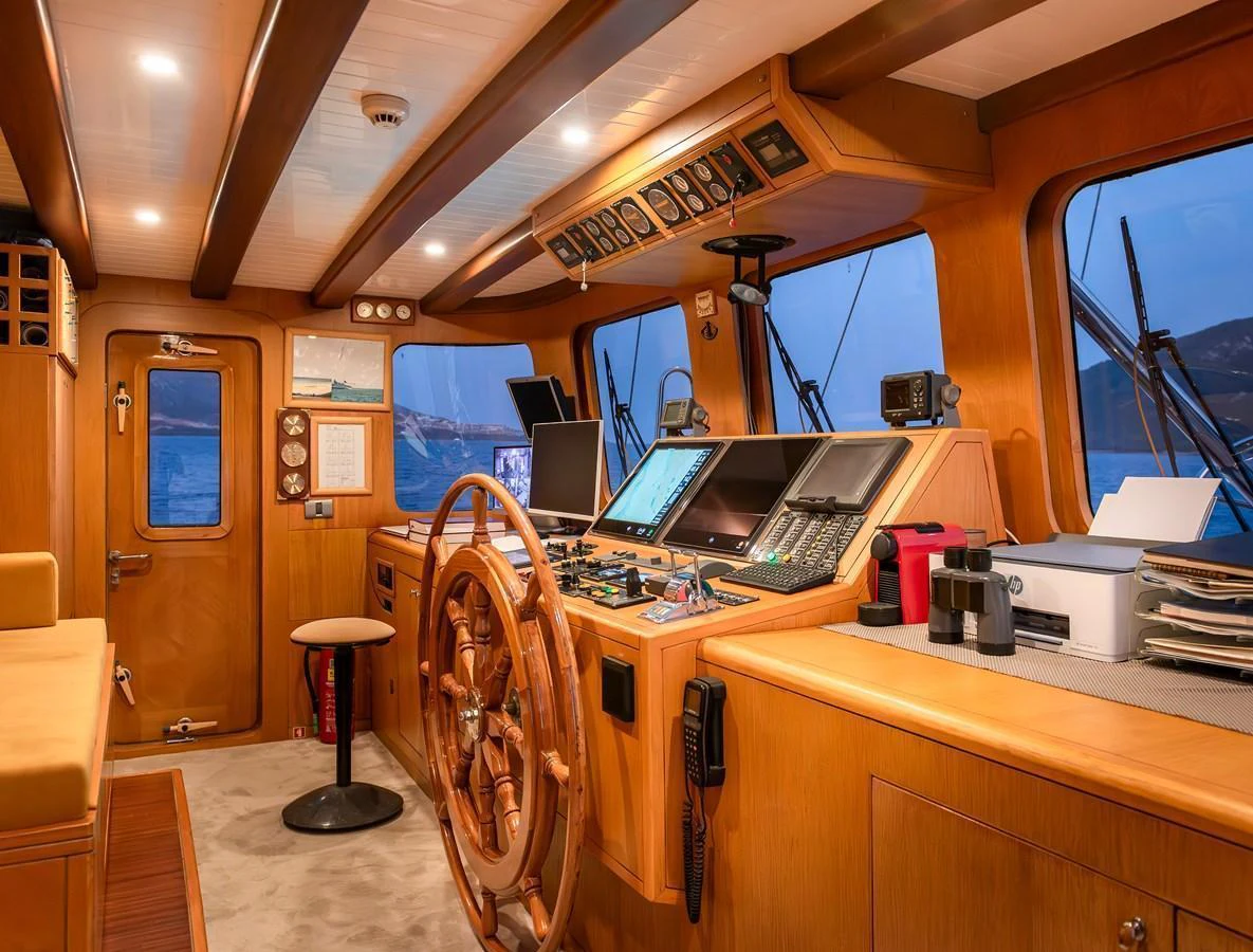 The helm of the yacht features a classic wooden steering wheel and an array of modern navigation equipment. aboard AEGEAN Yacht for Sale