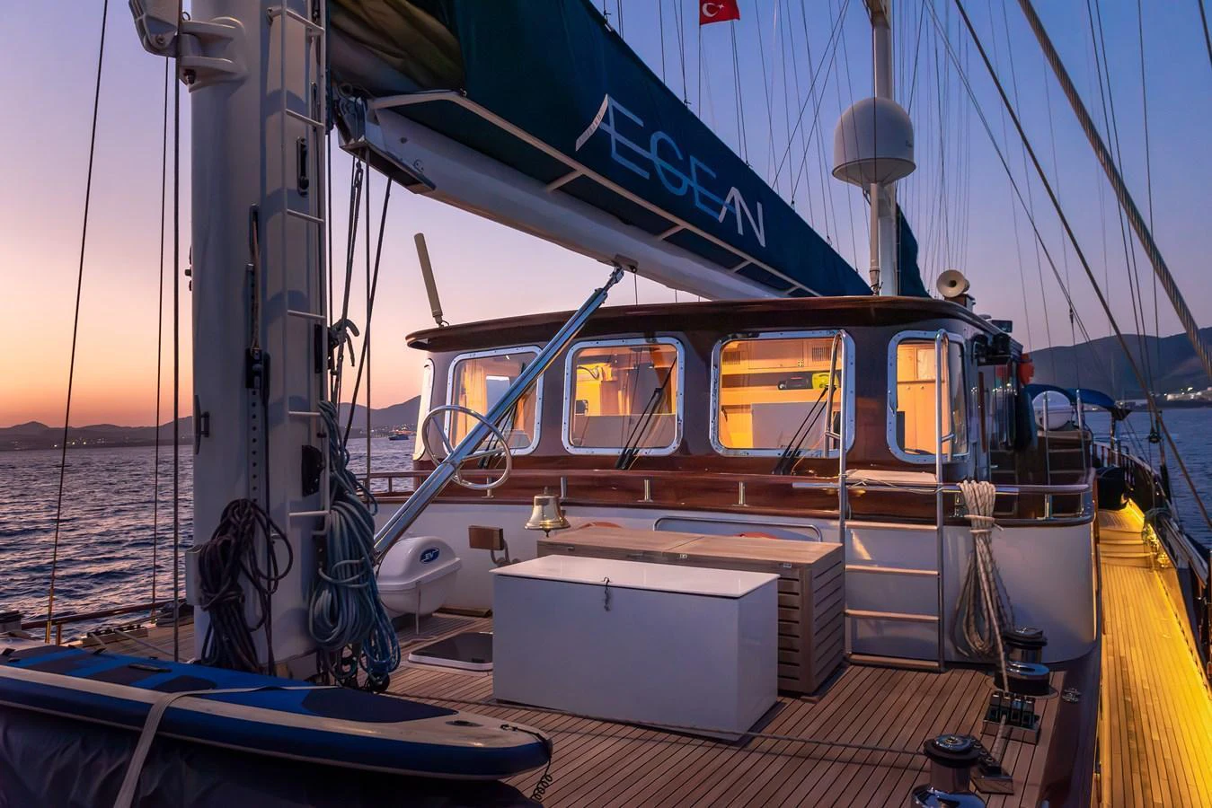 The yacht's deck is beautifully illuminated at dusk, showcasing a serene and inviting atmosphere. aboard AEGEAN Yacht for Sale