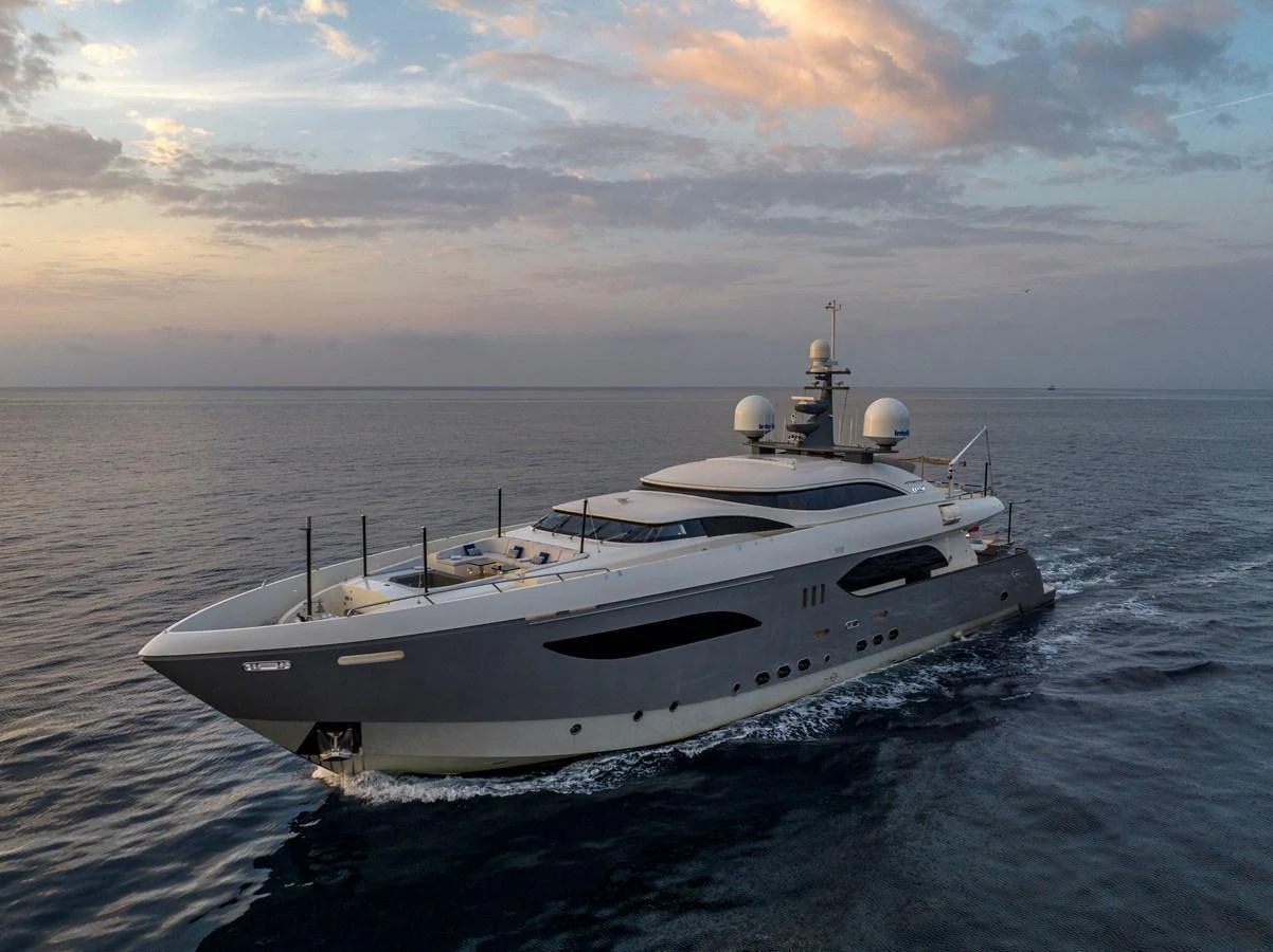 A sleek and modern yacht glides through calm waters at sunset. aboard GEMS II Yacht for Sale