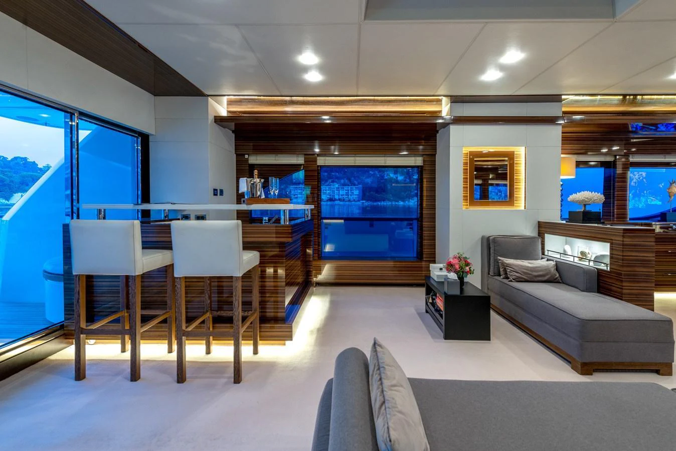 The yacht's salon features modern furnishings, a bar area, and large windows offering stunning views. aboard GEMS II Yacht for Sale