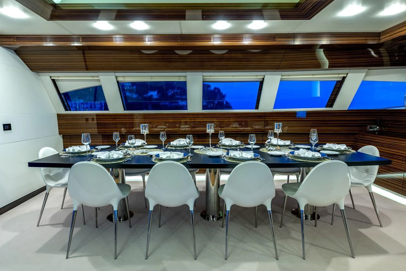 The yacht's dining area features a sleek, modern table set for an elegant meal with panoramic windows providing stunning views. aboard GEMS II Yacht for Sale