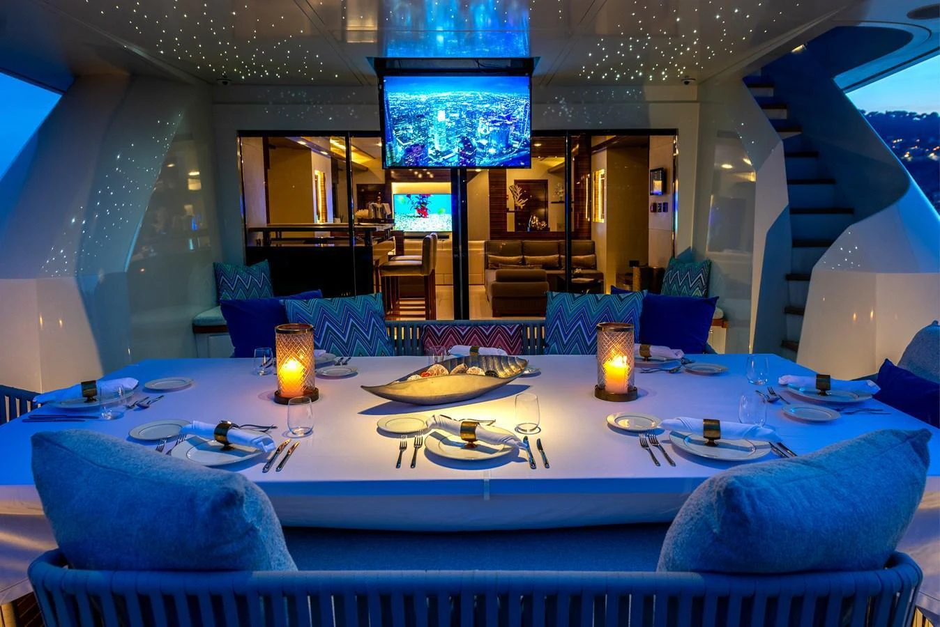 The aft deck features a luxurious dining area with ambient lighting and a view into the yacht's interior. aboard GEMS II Yacht for Sale