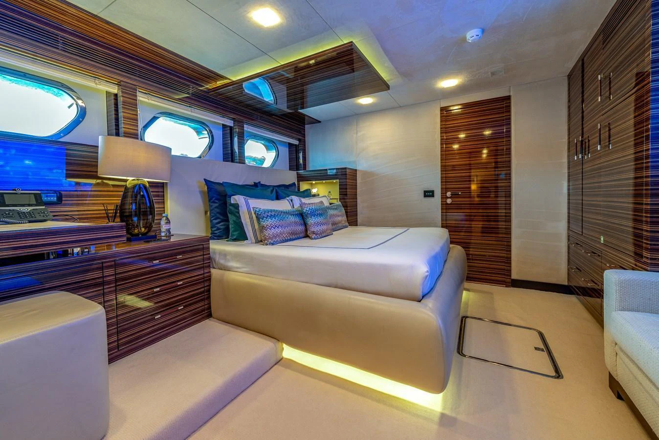 The master stateroom features a luxurious bed with elegant lighting and modern wood paneling. aboard GEMS II Yacht for Sale