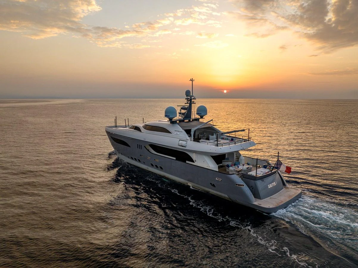 A luxurious yacht sails gracefully on calm waters during a stunning sunset. aboard GEMS II Yacht for Sale
