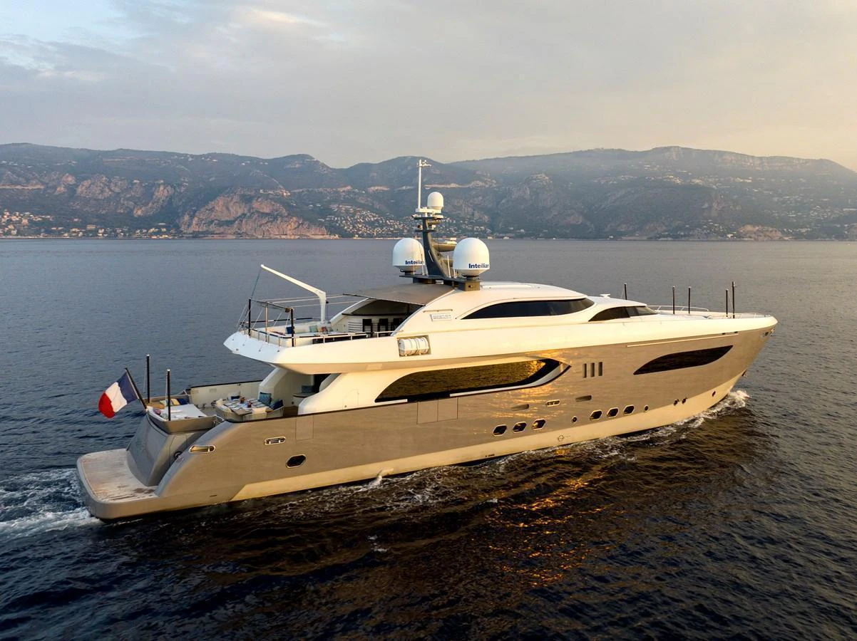 A luxurious yacht cruises through calm waters with a scenic mountainous backdrop. aboard GEMS II Yacht for Sale