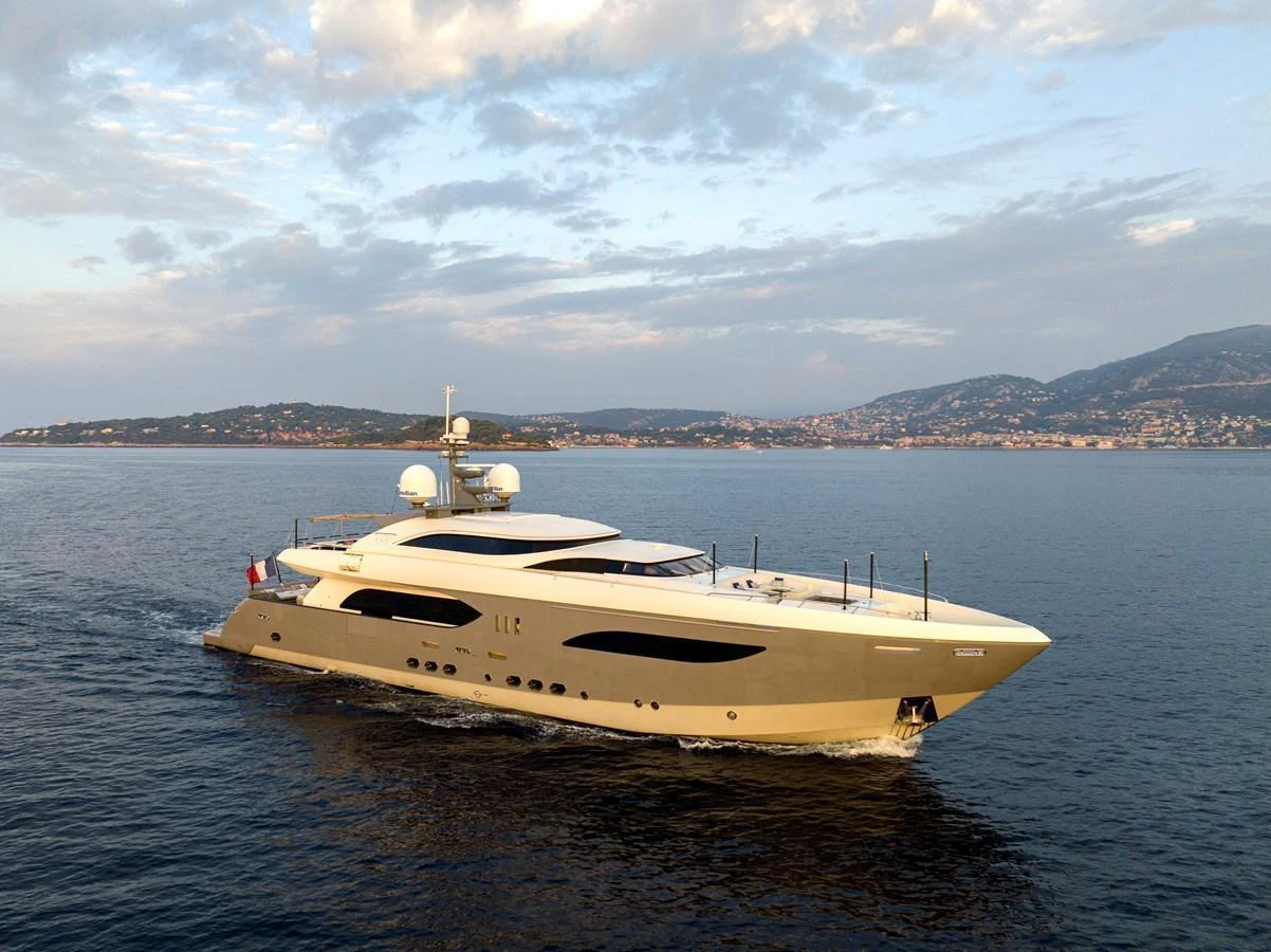 A sleek and modern yacht cruising on calm waters with a scenic coastal backdrop. aboard GEMS II Yacht for Sale