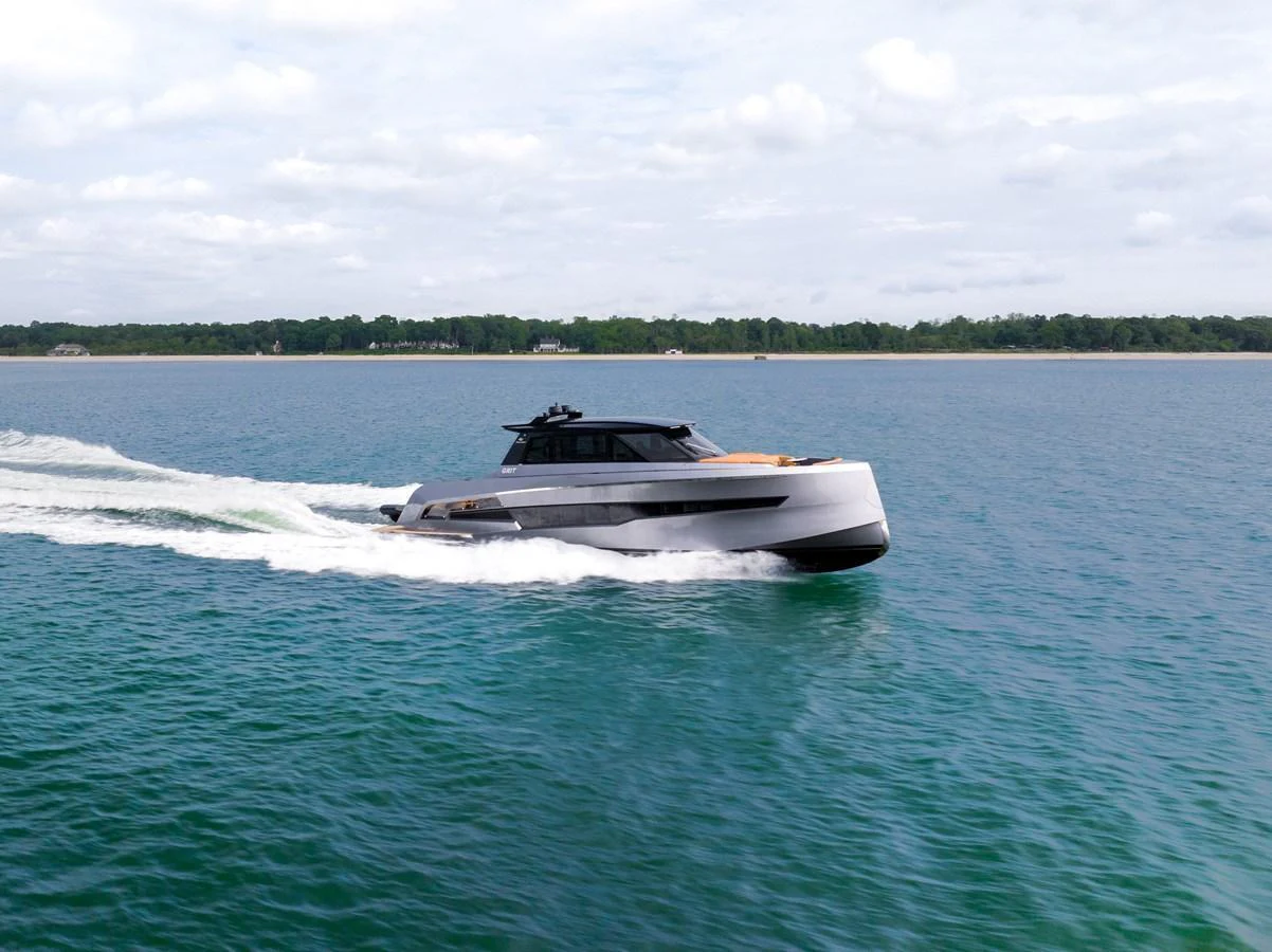 A sleek yacht cruises swiftly across calm waters under a partly cloudy sky. aboard GRIT Yacht for Sale