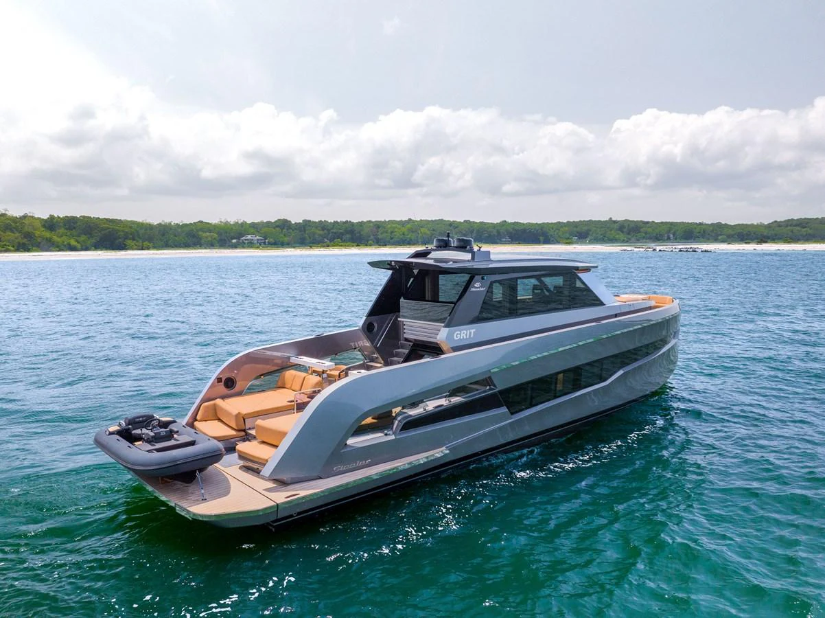 A sleek and modern yacht glides gracefully on calm waters with a scenic shoreline in the background. aboard GRIT Yacht for Sale