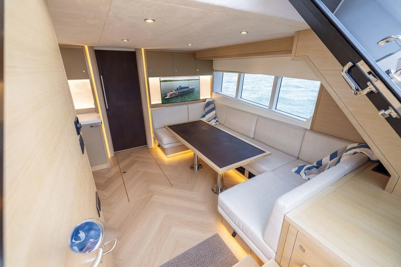 The salon features a cozy seating area with a table and large windows offering a view of the sea. aboard GRIT Yacht for Sale