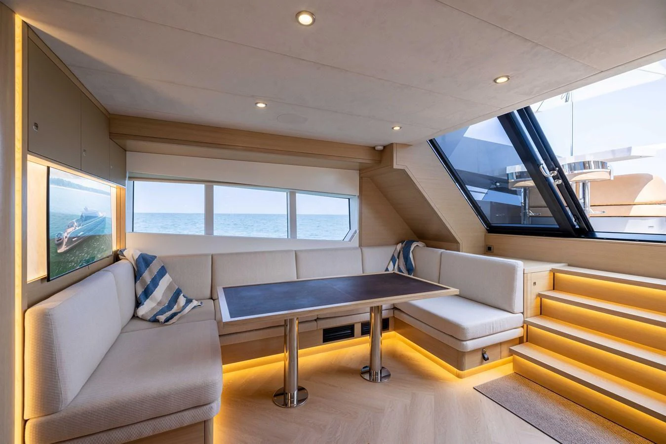 The salon features a cozy seating area with a table, illuminated by natural light and ambient lighting. aboard GRIT Yacht for Sale