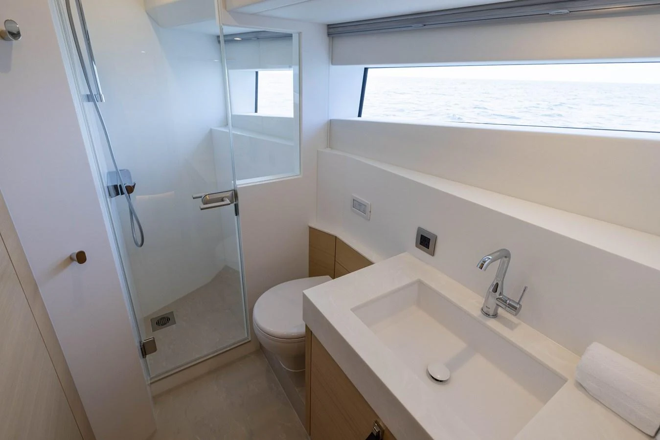 A modern yacht bathroom with sleek fixtures and a large window offering a sea view. aboard GRIT Yacht for Sale