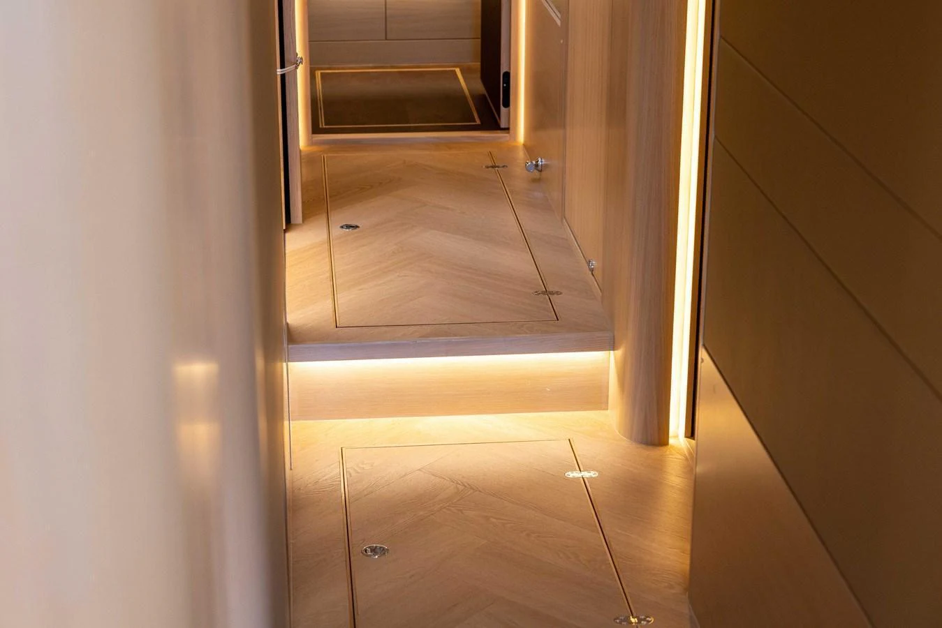 A sleek and modern hallway with ambient lighting and wooden flooring. aboard GRIT Yacht for Sale