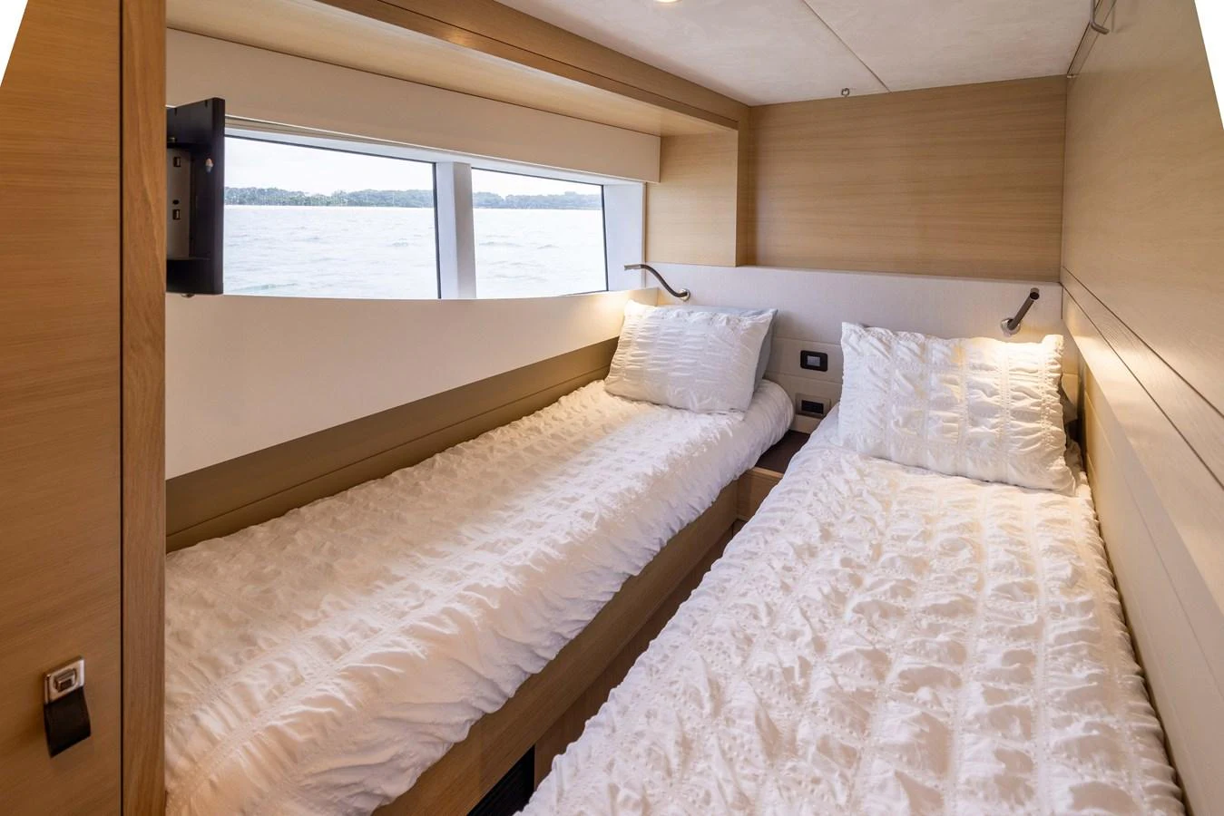 A cozy twin stateroom with large windows offering a serene view of the water. aboard GRIT Yacht for Sale