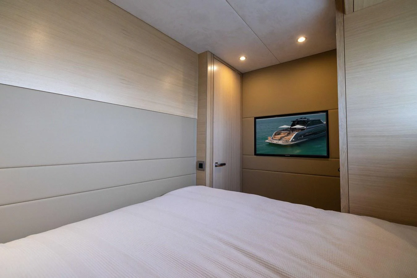A cozy stateroom featuring a comfortable bed and a wall-mounted TV displaying a yacht. aboard GRIT Yacht for Sale