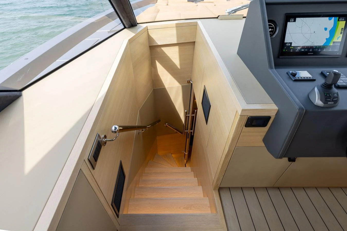 A sleek and modern staircase leads down from the helm area, showcasing elegant wood finishes and contemporary design. aboard GRIT Yacht for Sale