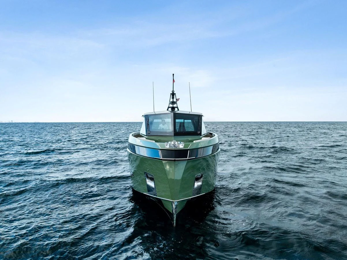 A sleek yacht is captured head-on, cruising on calm waters under a clear blue sky. aboard ANOTHER WORLD Yacht for Sale