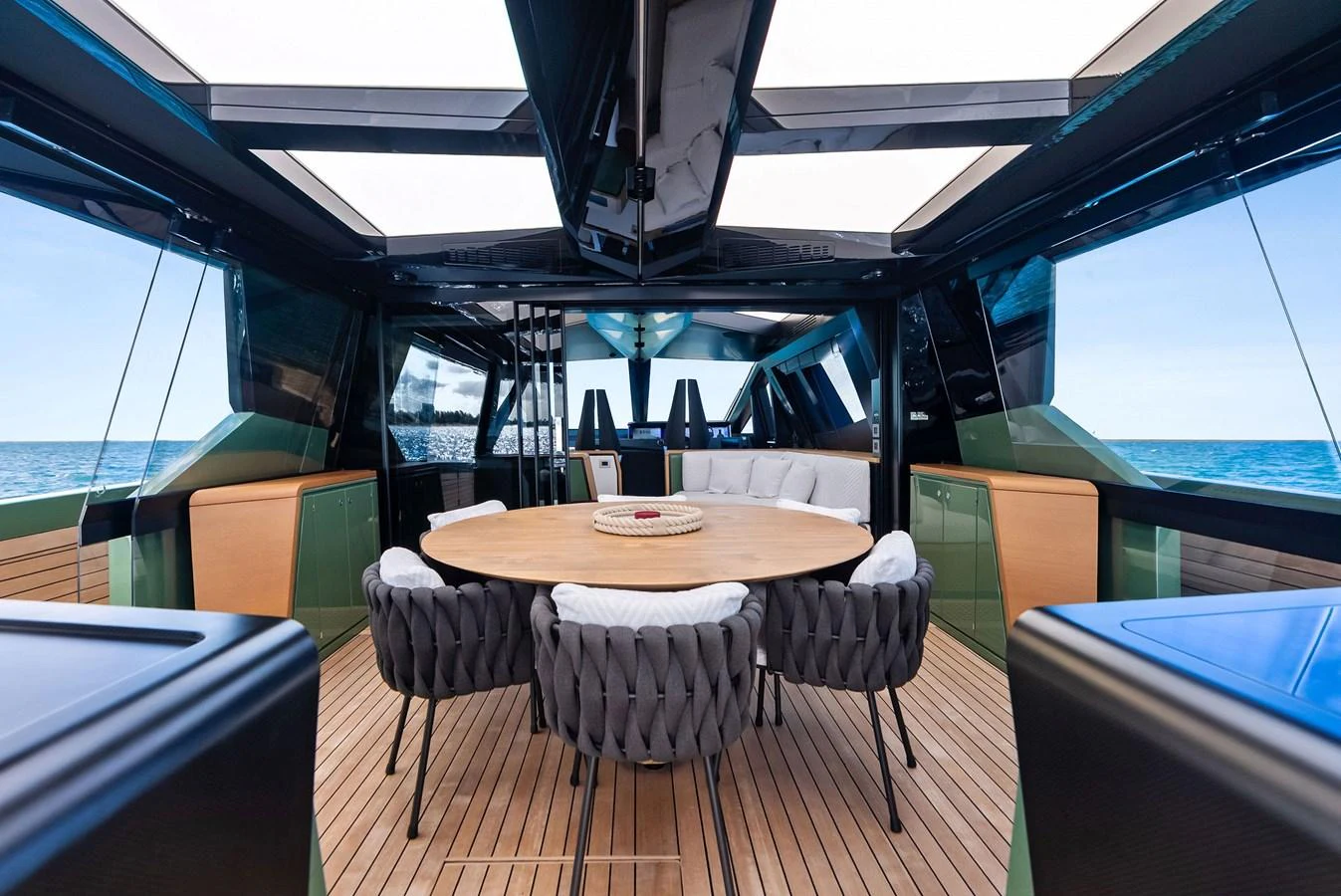 A luxurious dining area with a large round table and comfortable seating, surrounded by panoramic windows offering stunning sea views. aboard ANOTHER WORLD Yacht for Sale