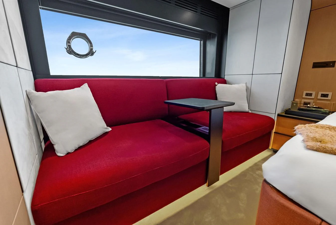 The stateroom features a plush red sofa with a large window offering a stunning view. aboard ANOTHER WORLD Yacht for Sale