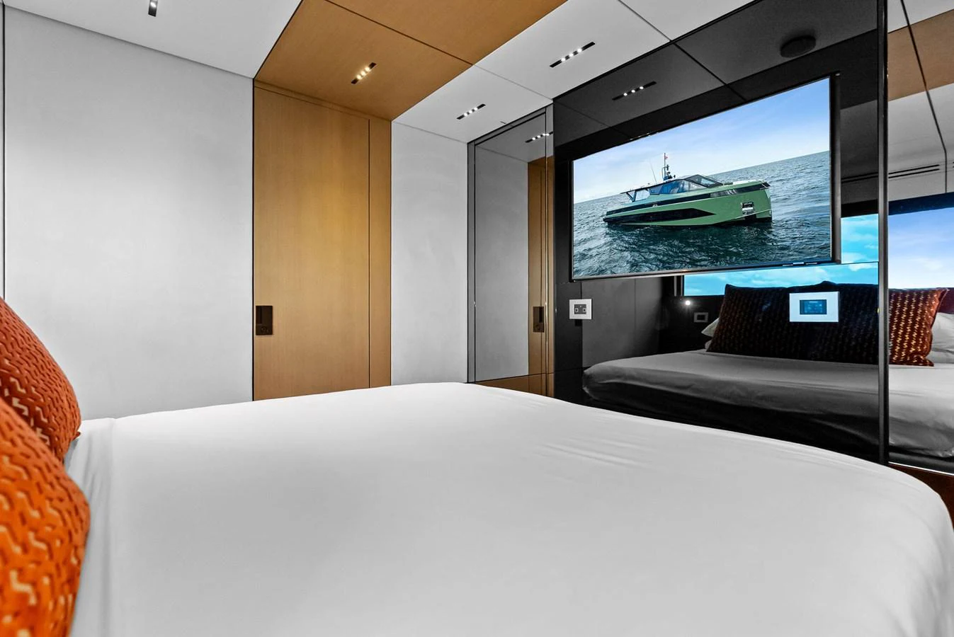 A modern stateroom featuring a large bed, wooden accents, and a flat-screen TV displaying a yacht. aboard ANOTHER WORLD Yacht for Sale