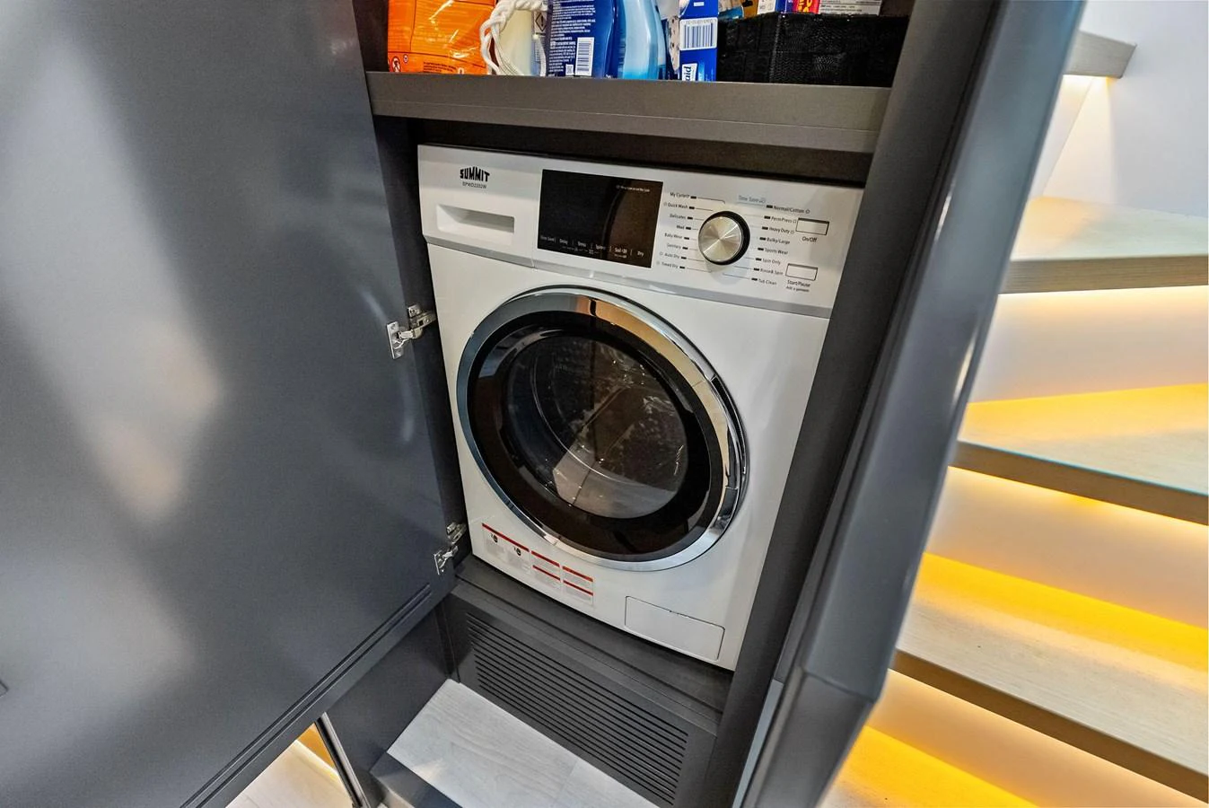 The image shows a neatly installed washing machine in a yacht's storage area. aboard ANOTHER WORLD Yacht for Sale