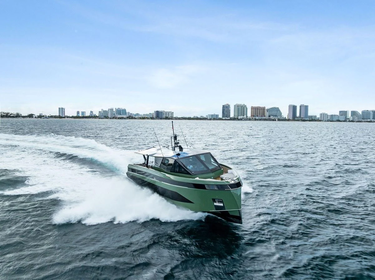 A sleek, modern yacht cruises swiftly through the water against a backdrop of a city skyline. aboard ANOTHER WORLD Yacht for Sale