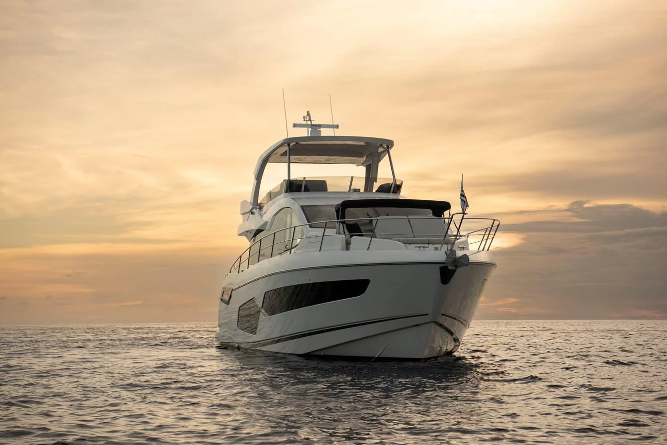 A sleek yacht glides gracefully on calm waters at sunset. aboard GAIA Yacht for Sale