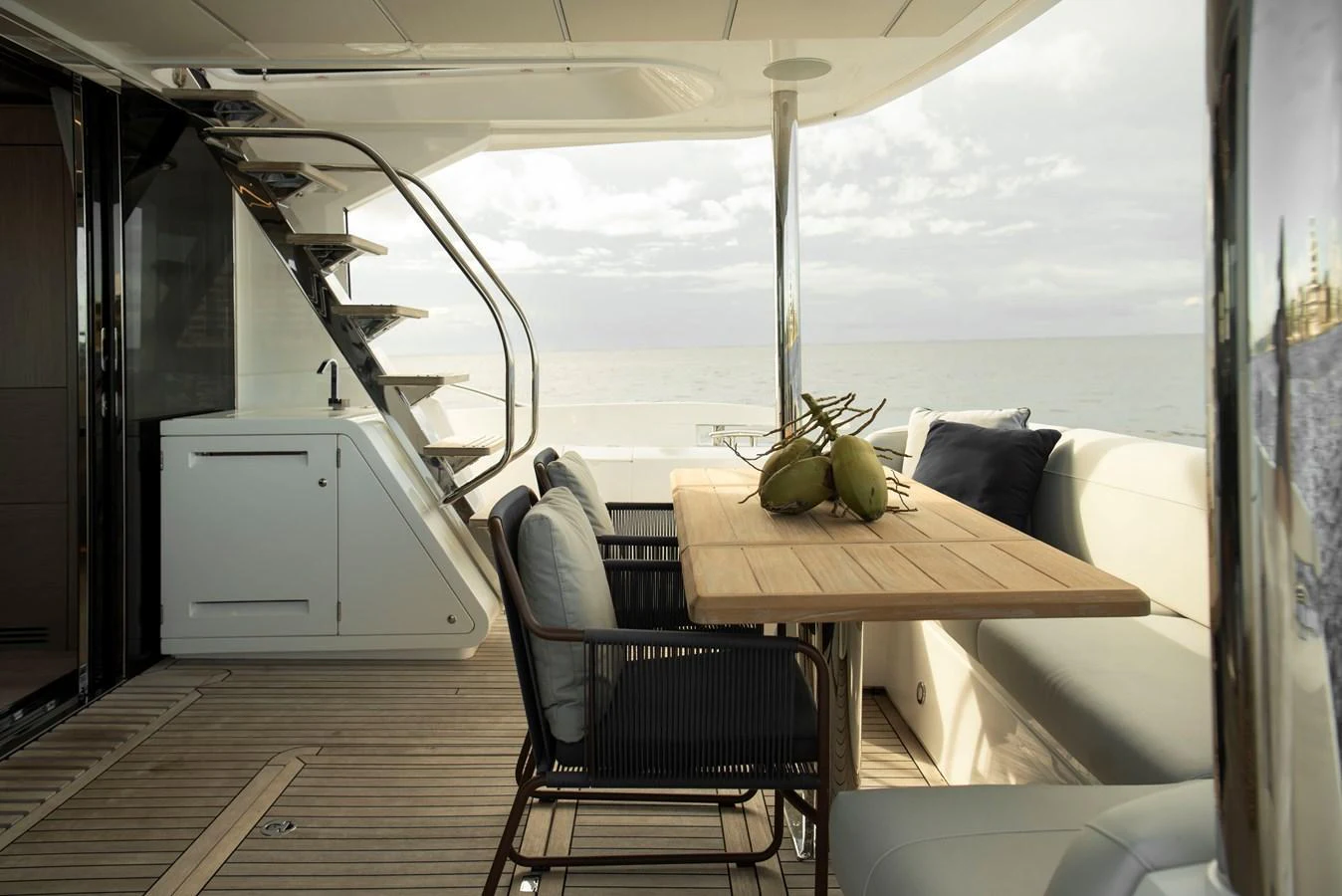 The aft deck features a stylish dining area with a wooden table and comfortable seating, offering a serene view of the sea. aboard GAIA Yacht for Sale