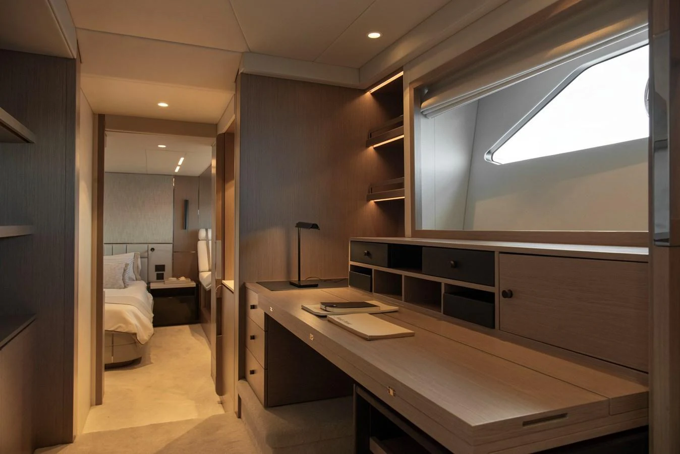 The stateroom features a sleek desk area with ample storage and a cozy bed in the background. aboard GAIA Yacht for Sale