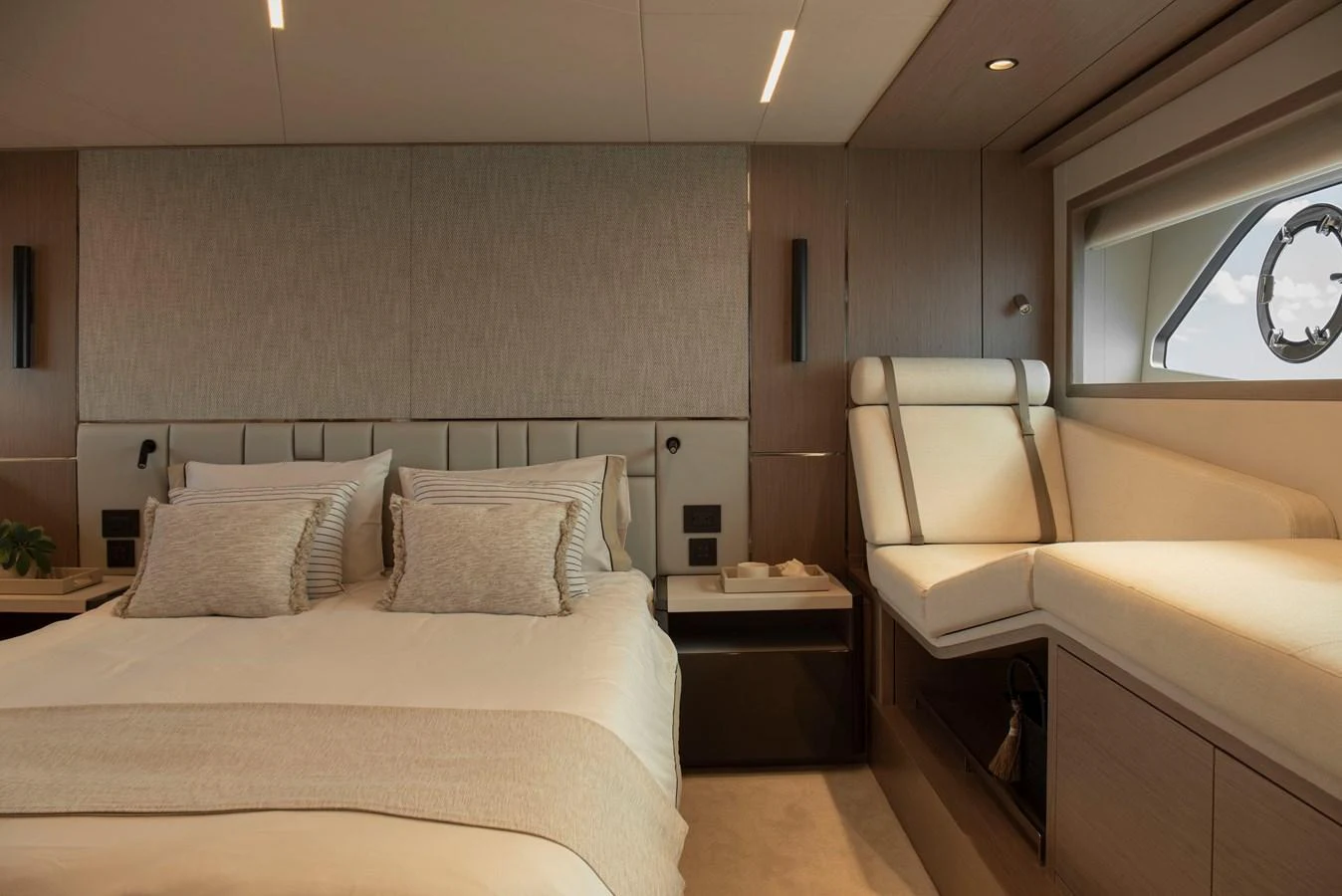 The stateroom features a luxurious bed and a cozy seating area by the window. aboard GAIA Yacht for Sale