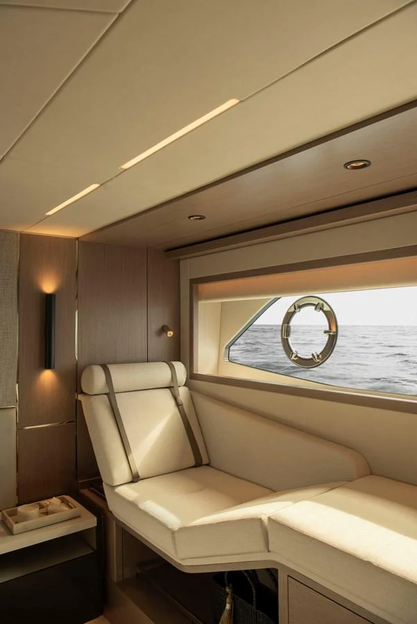 A cozy interior lounge area with a comfortable seating arrangement and a view of the sea through a porthole window. aboard GAIA Yacht for Sale