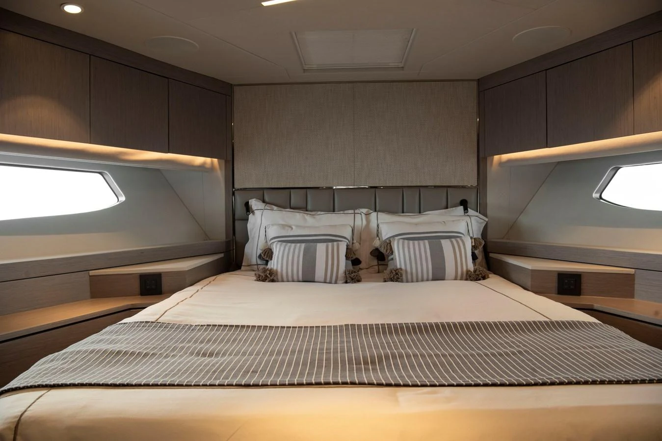 The stateroom features a luxurious bed with elegant bedding and ample natural light from side windows. aboard GAIA Yacht for Sale