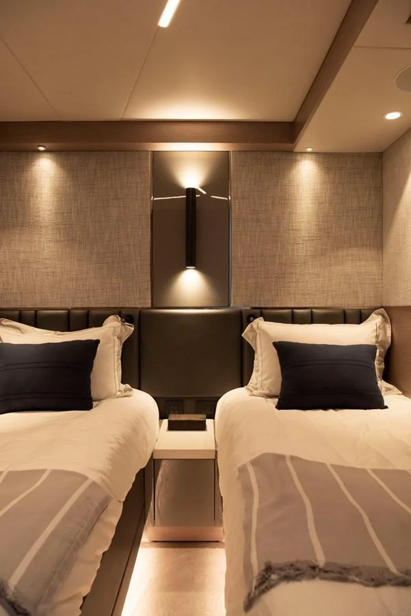 The twin stateroom features two comfortable beds with elegant bedding and soft ambient lighting. aboard GAIA Yacht for Sale