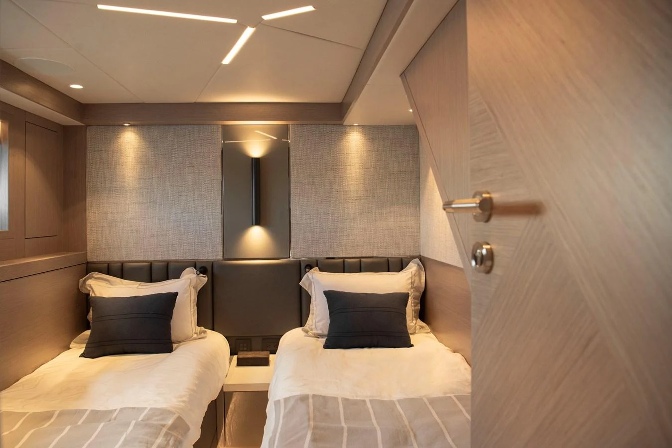 A cozy twin stateroom with modern lighting and elegant bedding. aboard GAIA Yacht for Sale