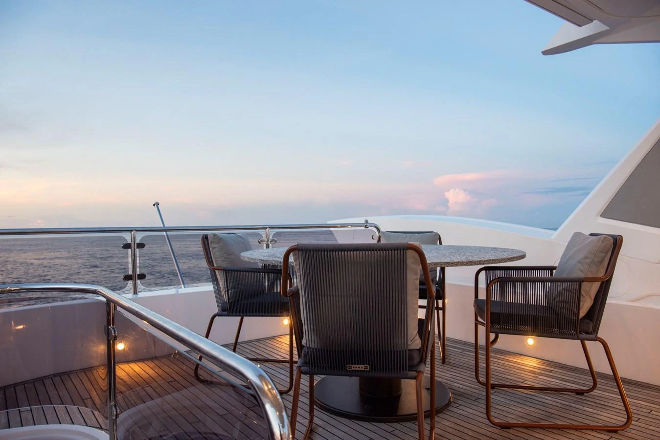 The aft deck features a stylish outdoor dining area with a round table and comfortable chairs, perfect for enjoying meals with a view of the sea. aboard GAIA Yacht for Sale