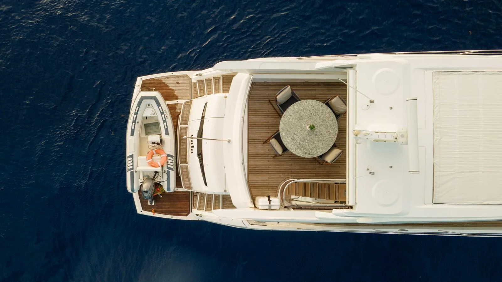 Aerial view of a yacht's aft deck featuring a dining area and a tender. aboard GAIA Yacht for Sale