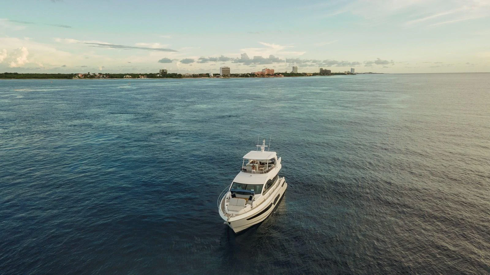 A luxurious yacht cruises peacefully on calm waters with a distant shoreline in the background. aboard GAIA Yacht for Sale