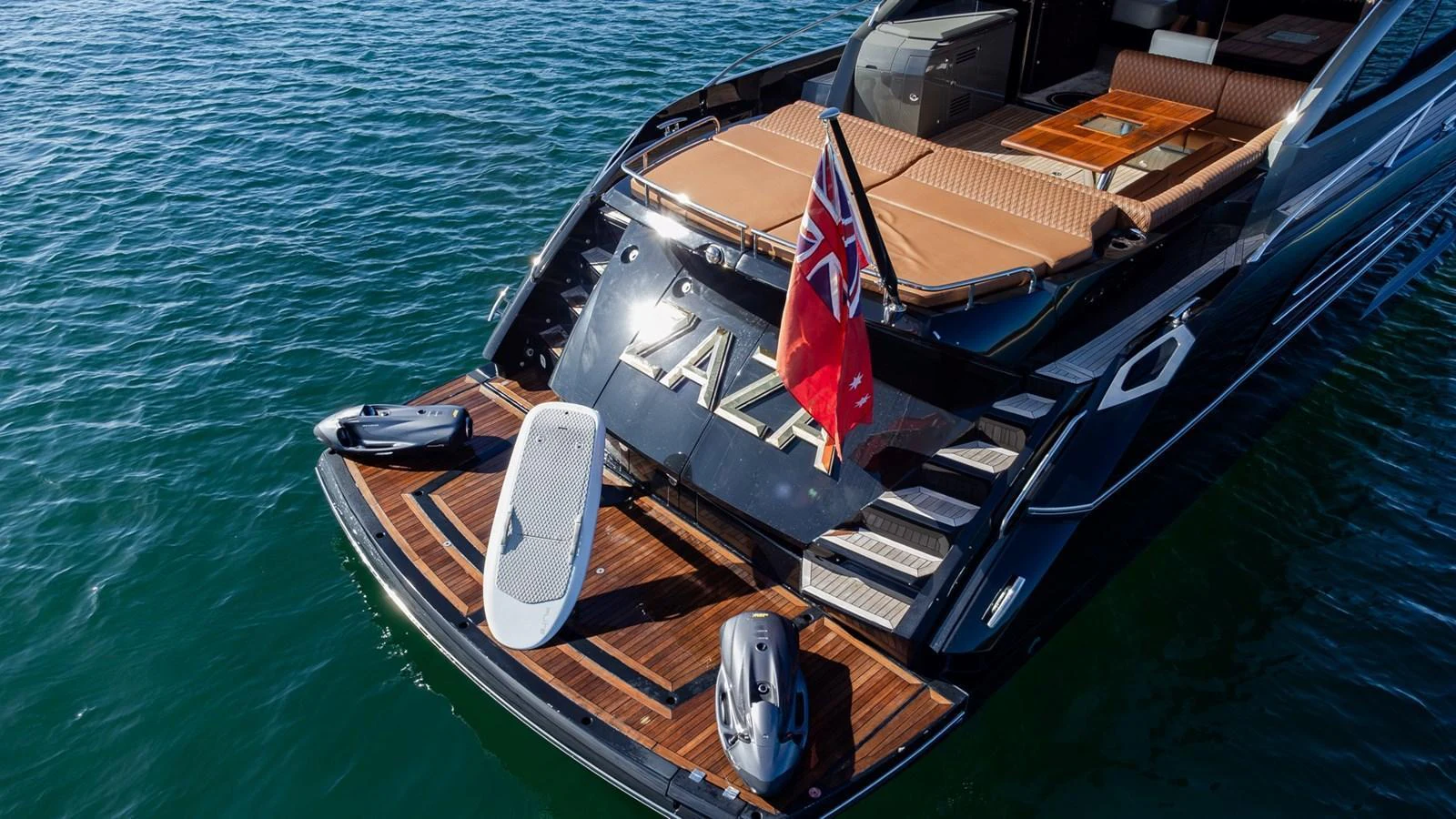 The yacht's aft deck features a luxurious lounging area with a flag proudly displayed. aboard ZAZA Yacht for Sale