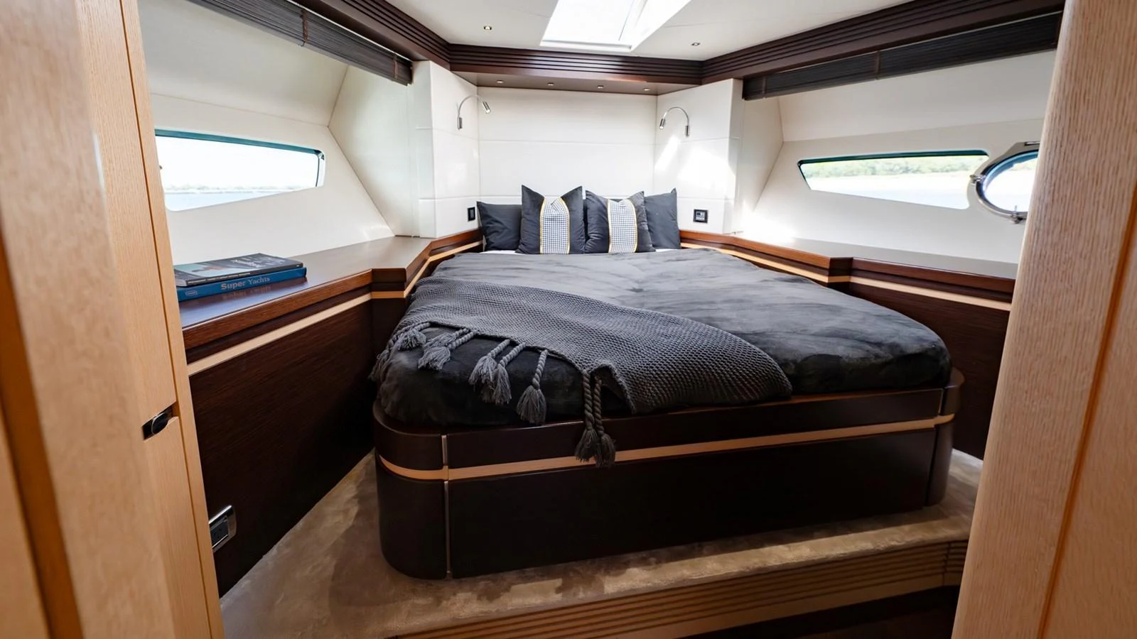The stateroom features a luxurious bed with plush bedding and ample natural light from the side windows. aboard ZAZA Yacht for Sale