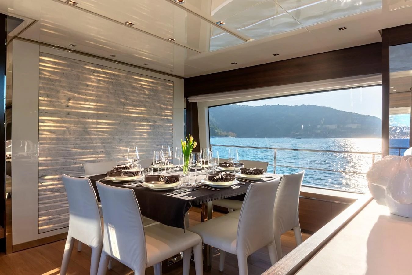 The yacht's dining area offers a luxurious setting with a stunning view of the water through large windows. aboard QUEEN MARTINA Yacht for Sale