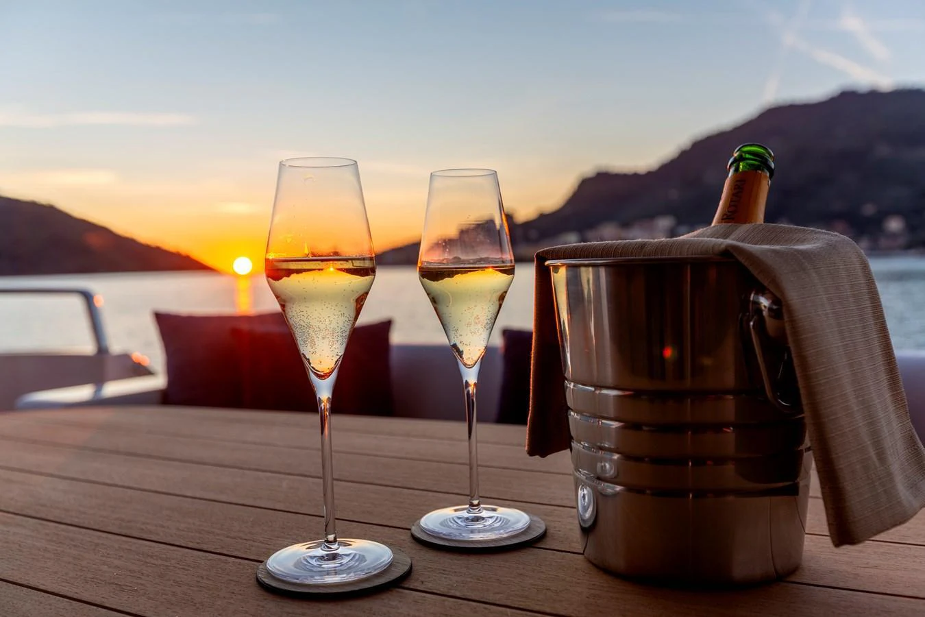A serene sunset view with champagne glasses and a bottle in an ice bucket on the yacht's deck. aboard QUEEN MARTINA Yacht for Sale