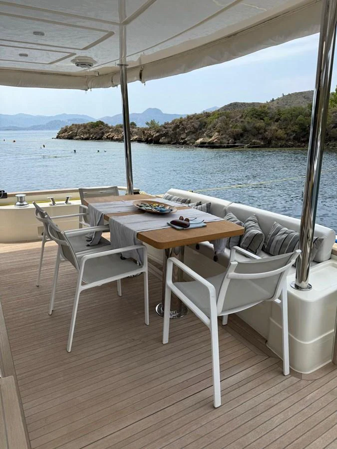 a table and chairs on a deck overlooking a body of water aboard NEVER TOO LATE Yacht for Sale