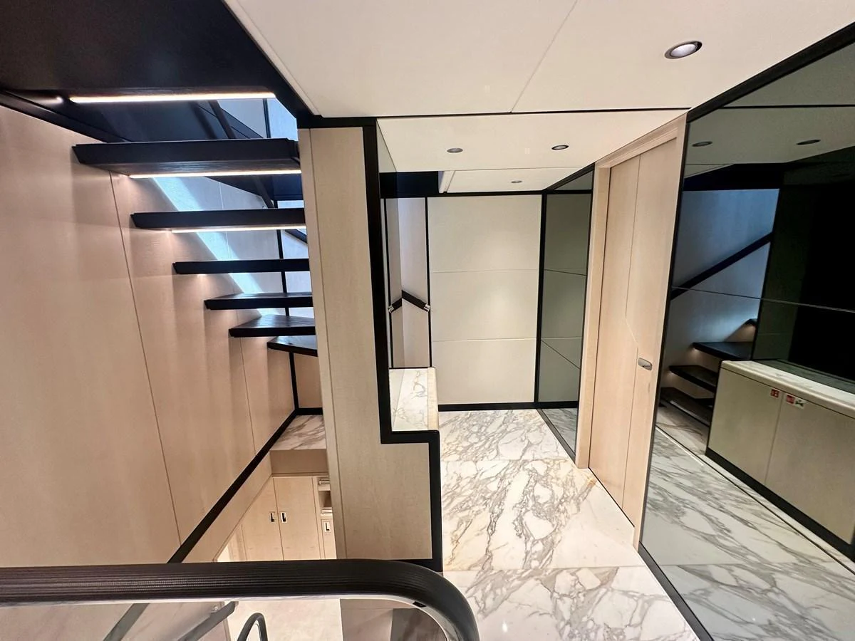 A modern yacht interior featuring a sleek staircase with marble flooring and contemporary design elements. aboard OPTIMISM Yacht for Sale