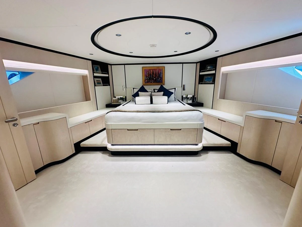 The master stateroom features a luxurious bed with modern decor and ample storage. aboard OPTIMISM Yacht for Sale