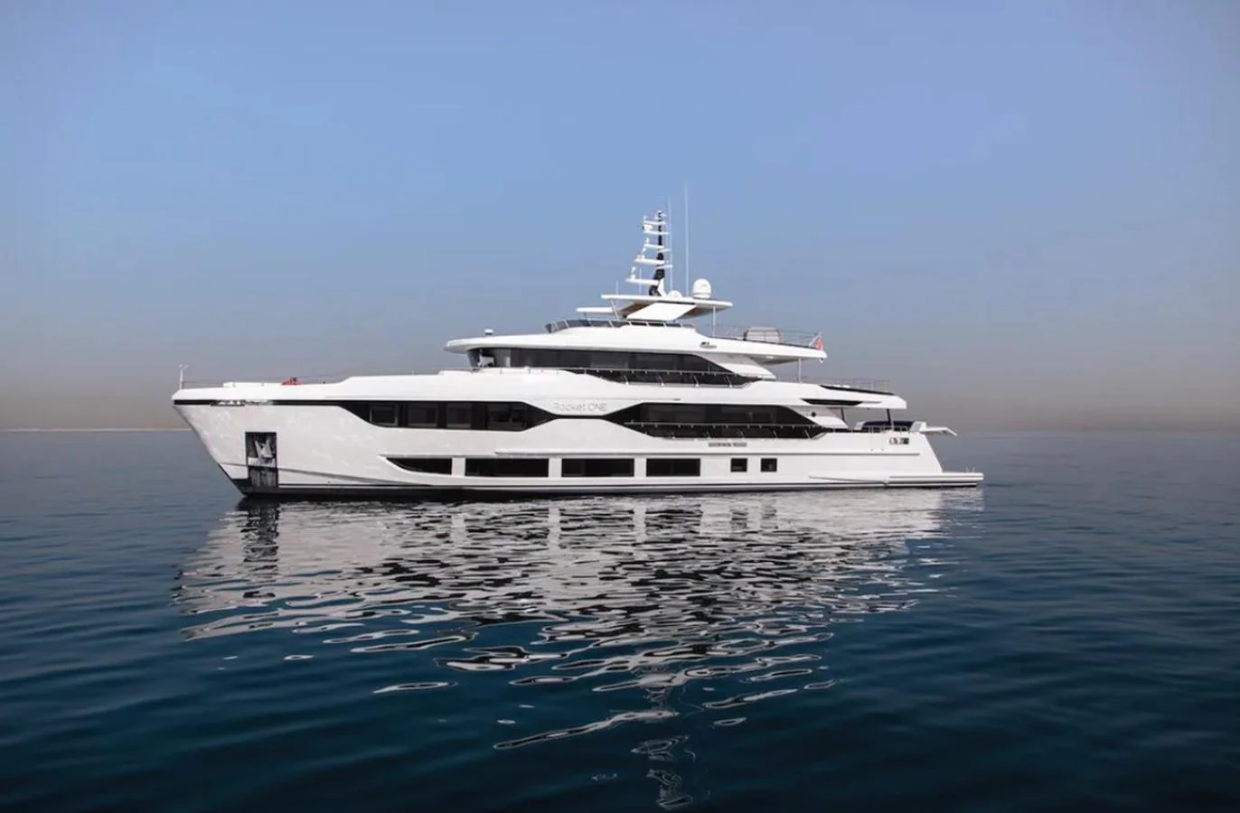 A sleek and modern yacht glides gracefully on calm waters under a clear sky. aboard OPTIMISM Yacht for Sale