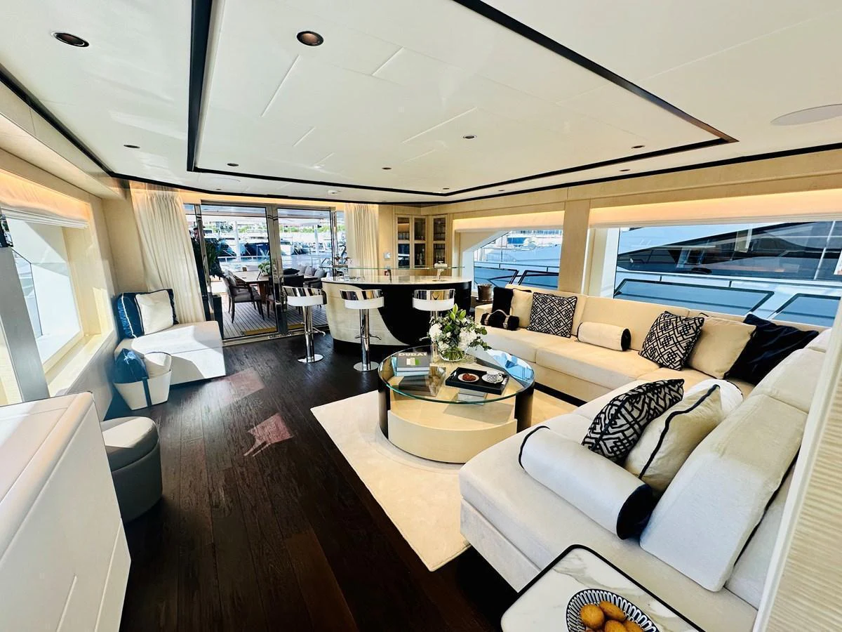 The salon features elegant furnishings with ample seating and large windows offering scenic views. aboard OPTIMISM Yacht for Sale