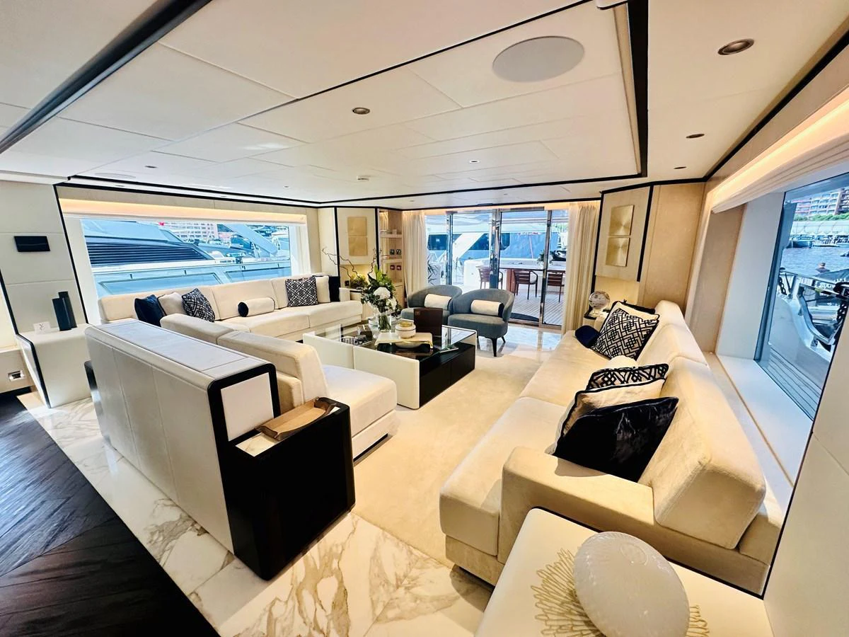 The salon features luxurious seating with ample natural light and elegant decor. aboard OPTIMISM Yacht for Sale