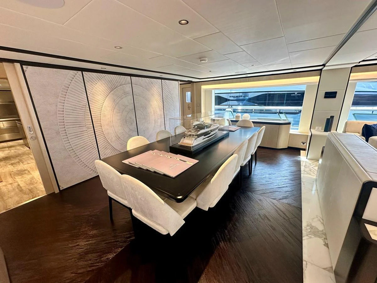 The yacht's dining area features a sleek, modern design with a large table and comfortable seating. aboard OPTIMISM Yacht for Sale