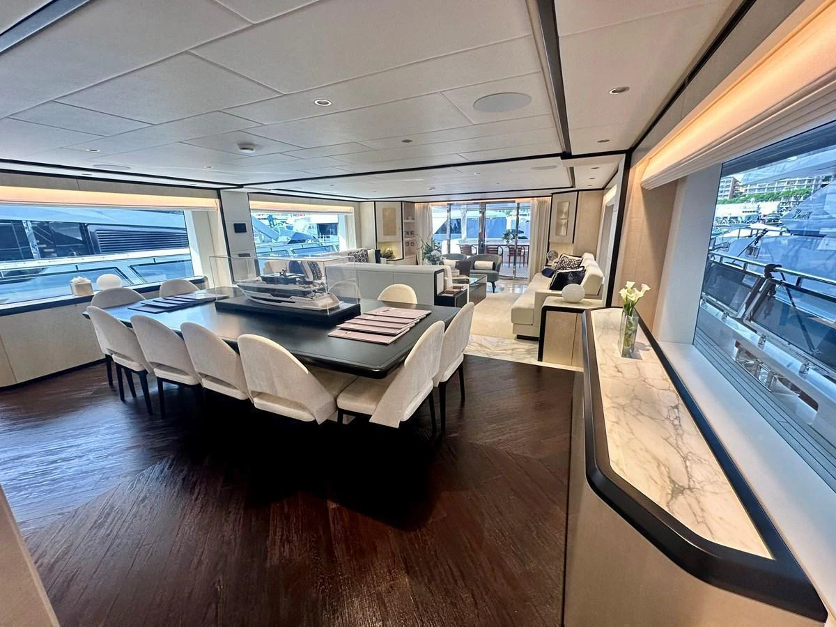 The yacht's dining area features a spacious table with elegant seating and ample natural light. aboard OPTIMISM Yacht for Sale